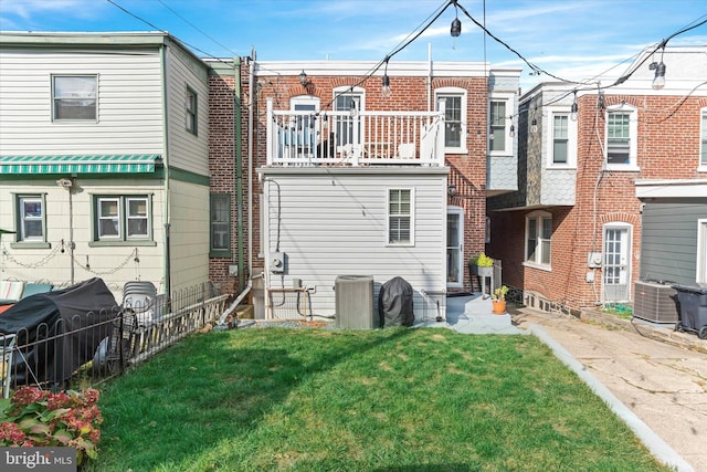 rear view of house with central air condition unit and a yard