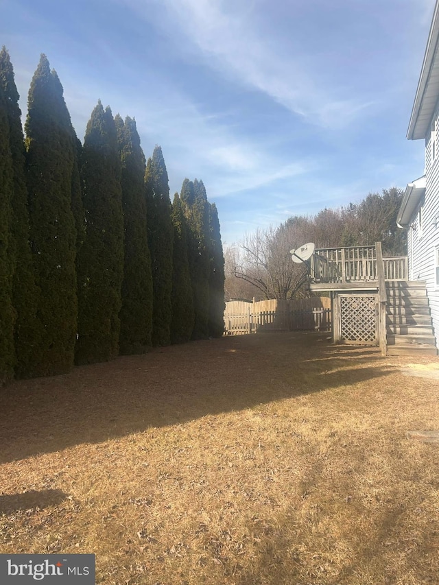 view of yard with a deck, stairway, and fence