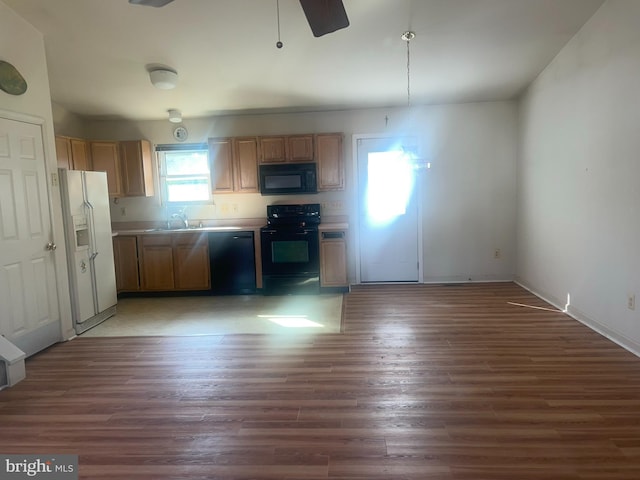 kitchen featuring a sink, black appliances, wood finished floors, and light countertops