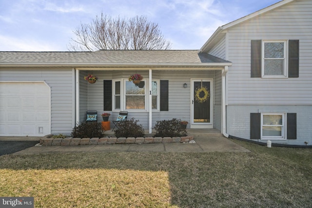 split level home with a garage, roof with shingles, a porch, and a front lawn