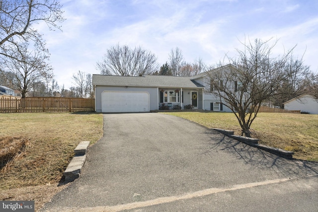 view of front of property featuring a garage, a front lawn, driveway, and fence