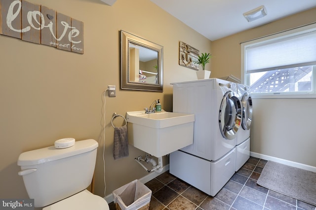 laundry area featuring a sink, baseboards, laundry area, and washing machine and clothes dryer