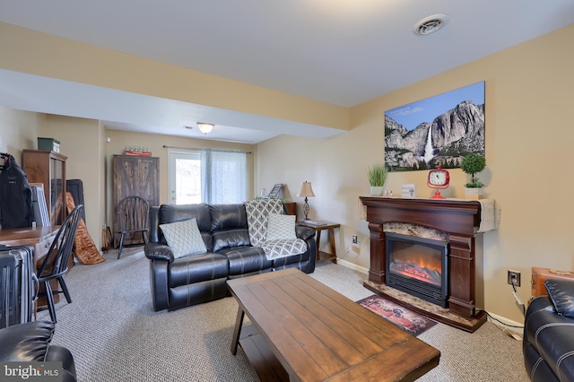 living area with a glass covered fireplace, carpet flooring, baseboards, and visible vents