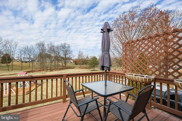 wooden terrace with outdoor dining area and a yard