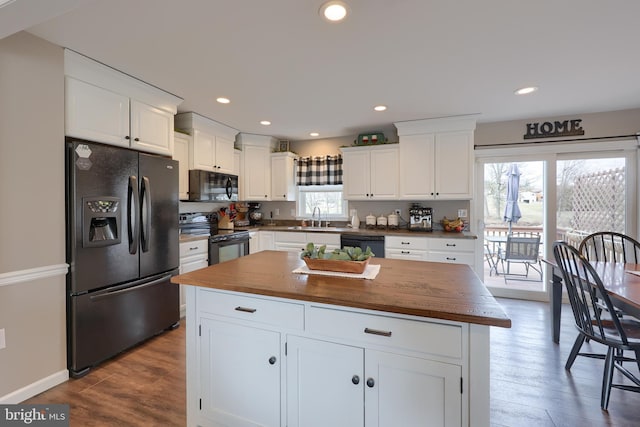 kitchen with wood counters, black appliances, white cabinets, and a sink