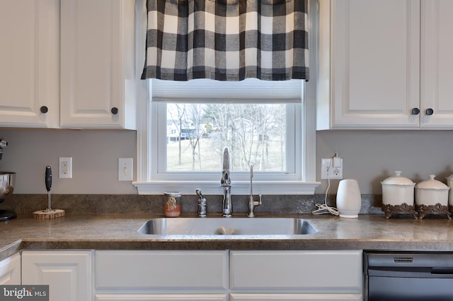 kitchen with a sink, dishwashing machine, dark countertops, and white cabinets