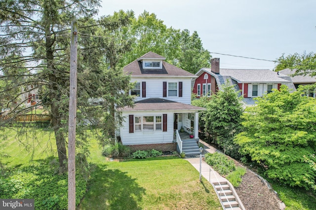 traditional style home with a front yard and a shingled roof