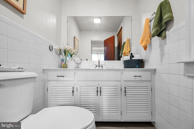 bathroom featuring toilet, tile walls, and vanity