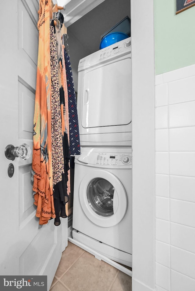 laundry area featuring tile patterned floors, laundry area, and stacked washing maching and dryer