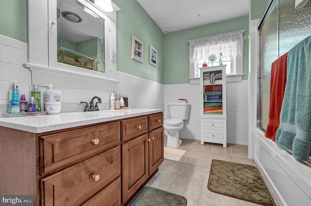 bathroom featuring tile patterned flooring, toilet, vanity, and tile walls