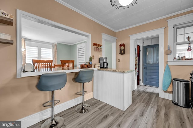 kitchen with light wood-type flooring, white cabinets, crown molding, and light countertops