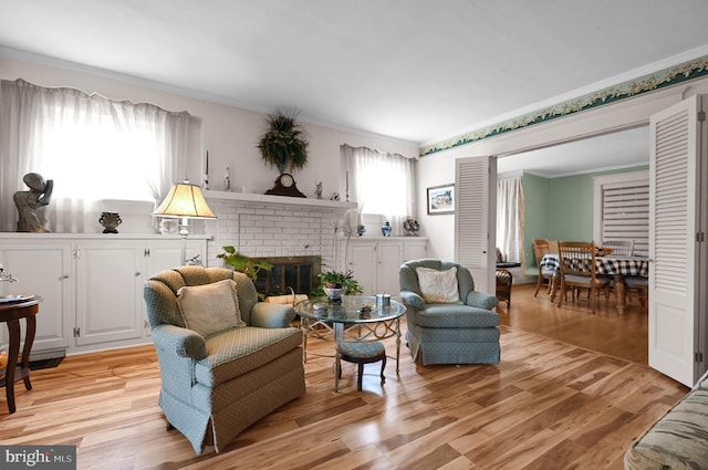 living area featuring crown molding, a brick fireplace, and light wood-type flooring