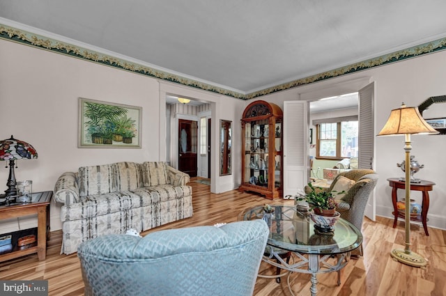 living area featuring baseboards, wood finished floors, and crown molding