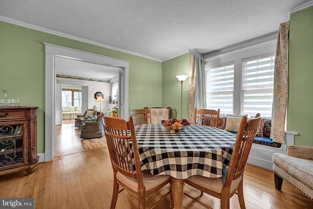 dining area with baseboards, light wood-style flooring, and ornamental molding