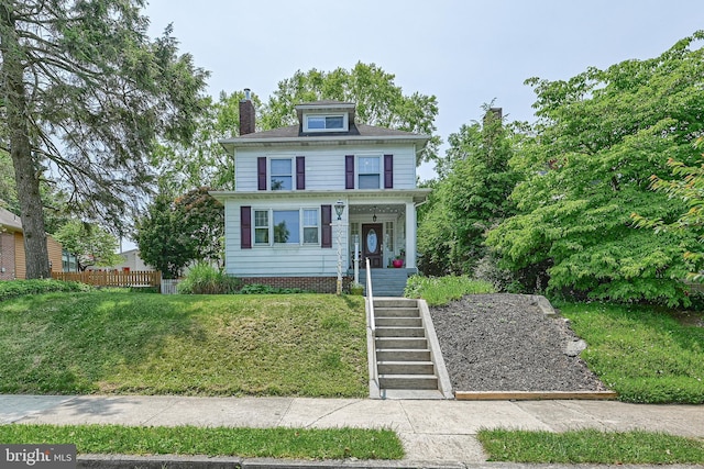 american foursquare style home with stairway, a chimney, a front lawn, and fence