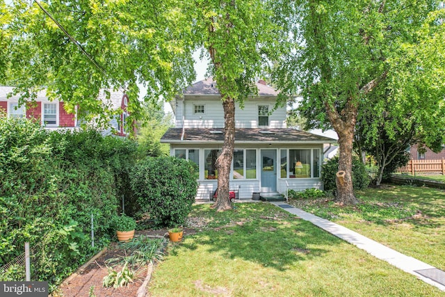 view of front of house featuring fence, a front lawn, and a sunroom