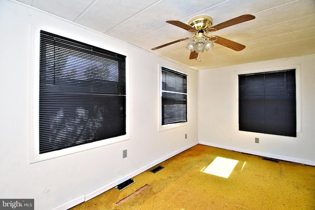 spare room with visible vents, a ceiling fan, and baseboards