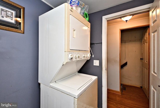 laundry area featuring stacked washer and dryer, wood finished floors, and laundry area