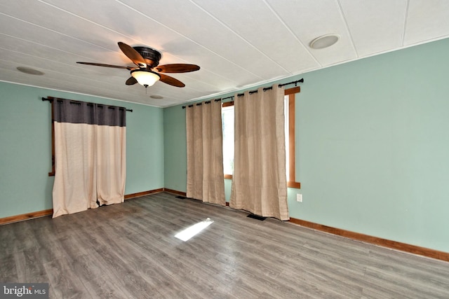 empty room with baseboards, wood finished floors, visible vents, and ceiling fan