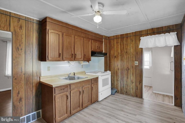 kitchen with light wood finished floors, visible vents, under cabinet range hood, white stove, and a sink