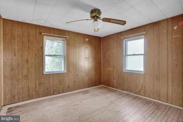 empty room with a healthy amount of sunlight, baseboards, a ceiling fan, and hardwood / wood-style flooring