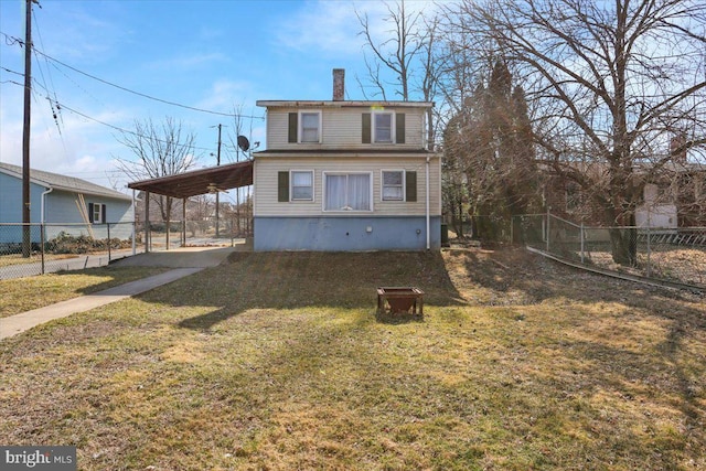 back of property featuring an attached carport, fence, a chimney, a yard, and driveway