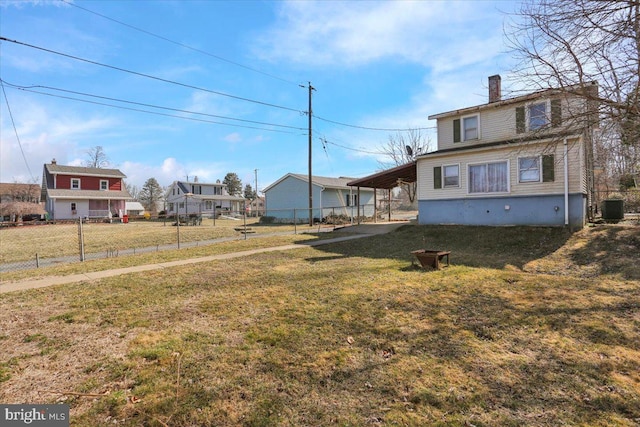 view of yard with a carport, central AC unit, and fence