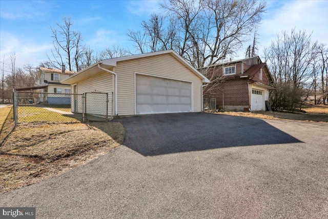 view of side of property with a gate, a detached garage, and fence