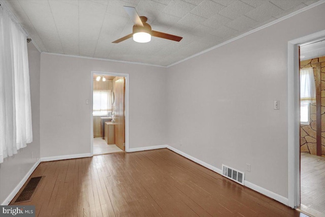 unfurnished bedroom featuring visible vents, baseboards, crown molding, and hardwood / wood-style flooring