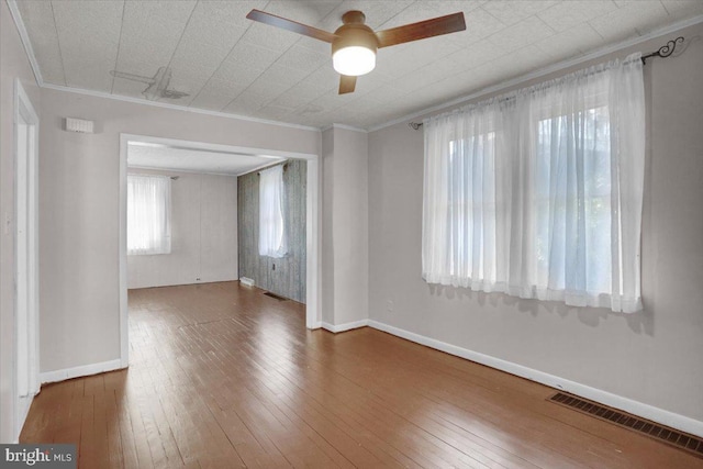 unfurnished room with hardwood / wood-style flooring, crown molding, and visible vents