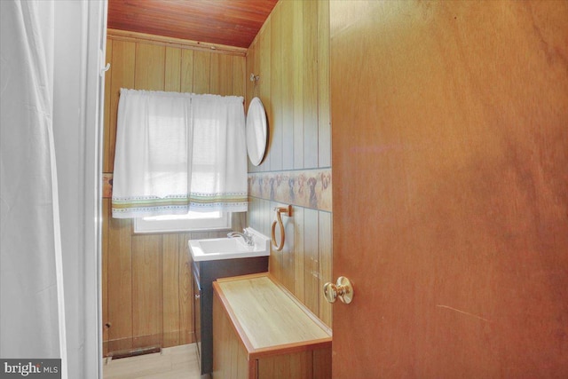 interior space featuring wooden walls, wood ceiling, and a sink