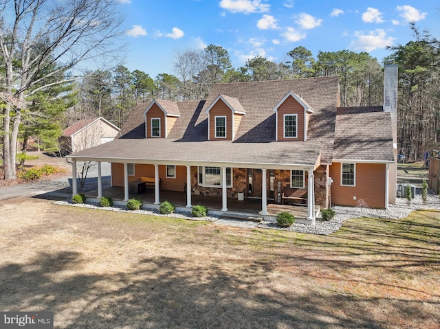 view of front facade with a porch, a front yard, stone siding, and a shingled roof