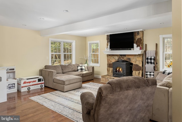 living room with beam ceiling, wood finished floors, recessed lighting, baseboards, and a wood stove