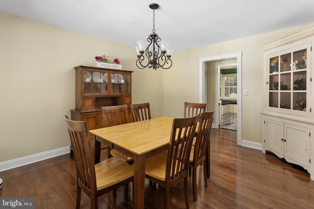 dining room featuring a chandelier, dark wood finished floors, and baseboards