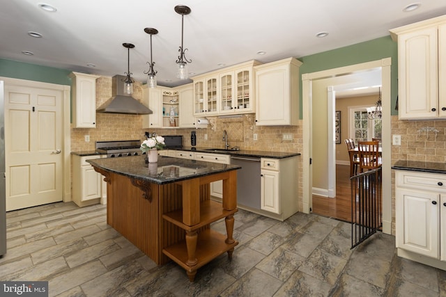 kitchen with open shelves, glass insert cabinets, pendant lighting, stainless steel dishwasher, and wall chimney range hood