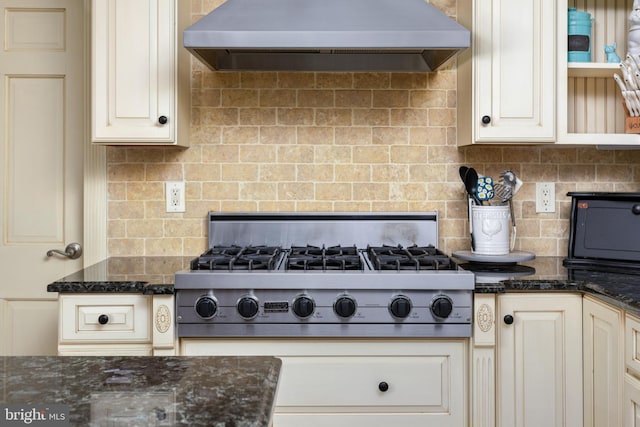 kitchen featuring dark stone countertops, open shelves, stainless steel gas stovetop, wall chimney exhaust hood, and backsplash