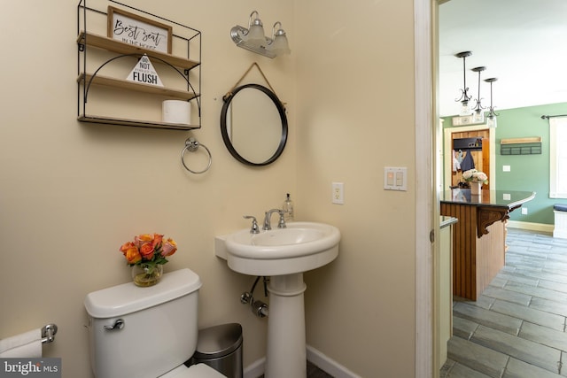 bathroom featuring toilet, baseboards, and a sink