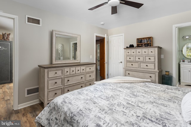 bedroom with dark wood finished floors, visible vents, ensuite bathroom, and baseboards