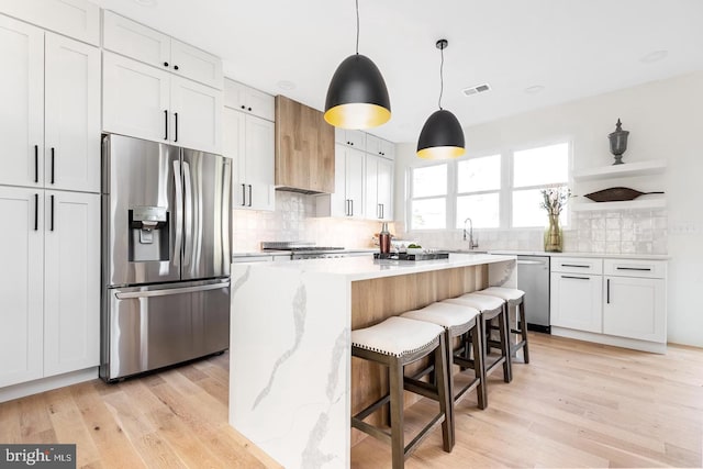 kitchen featuring visible vents, appliances with stainless steel finishes, light wood-type flooring, and open shelves