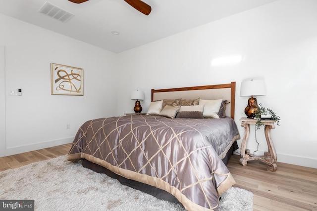 bedroom with visible vents, a ceiling fan, baseboards, and wood finished floors