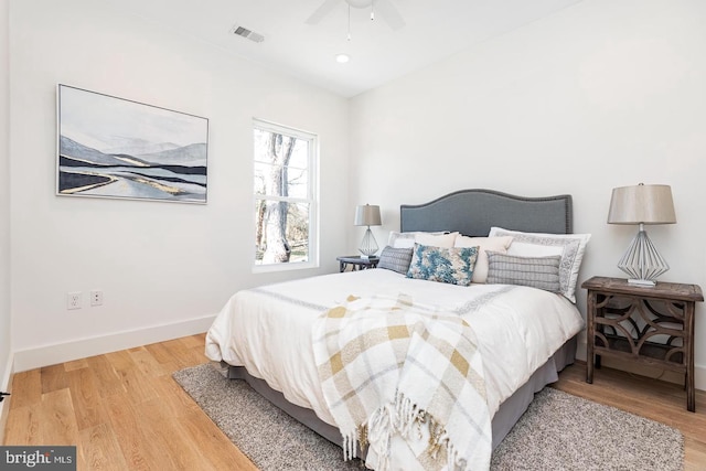 bedroom featuring ceiling fan, visible vents, baseboards, and wood finished floors