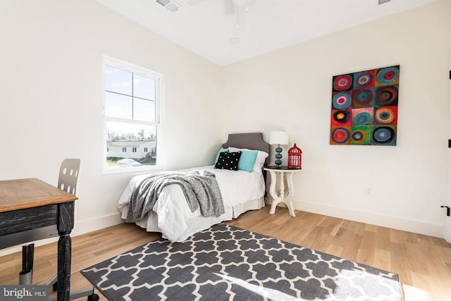 bedroom with visible vents, a ceiling fan, baseboards, and wood finished floors