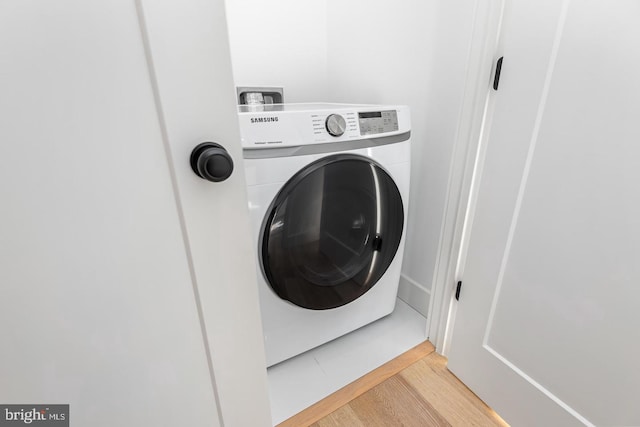 clothes washing area featuring light wood finished floors, laundry area, and washer / clothes dryer