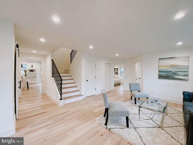 living room with baseboards, recessed lighting, stairs, a barn door, and light wood-type flooring