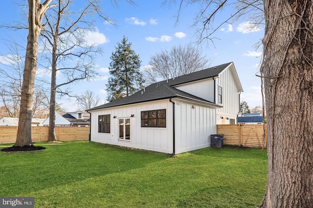 rear view of property with a yard, a fenced backyard, board and batten siding, and a shingled roof