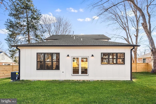 back of property with board and batten siding, fence, roof with shingles, a lawn, and cooling unit