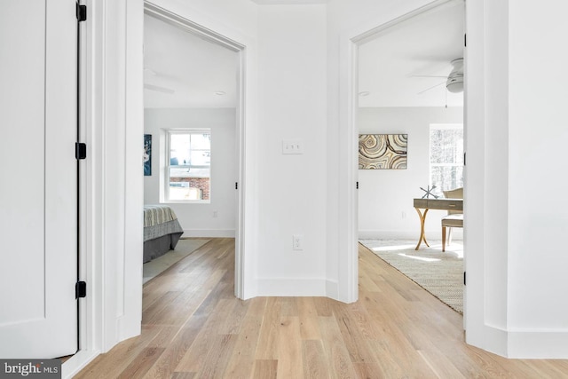 hall with baseboards and light wood-style floors