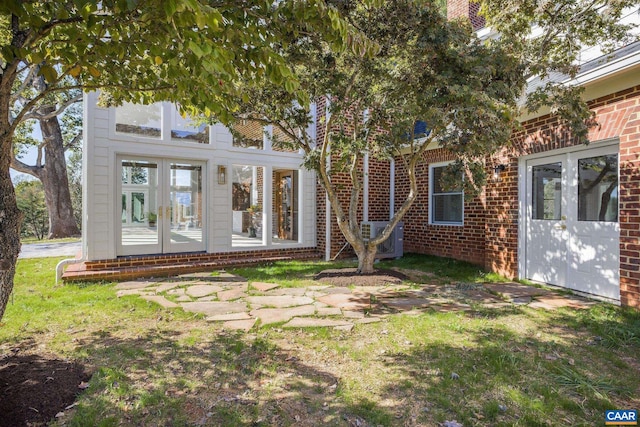 back of house featuring french doors, central air condition unit, brick siding, and a yard