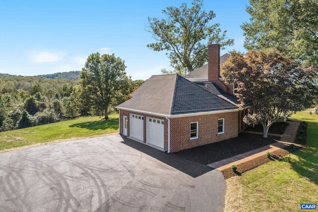 view of home's exterior featuring a lawn, brick siding, roof with shingles, and a chimney