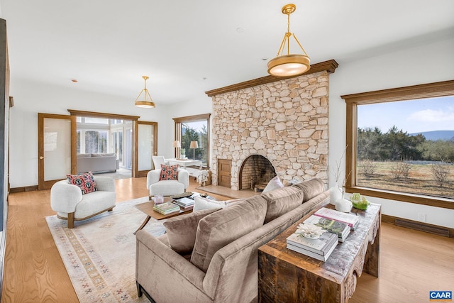 living room featuring light wood-type flooring, baseboards, and a fireplace